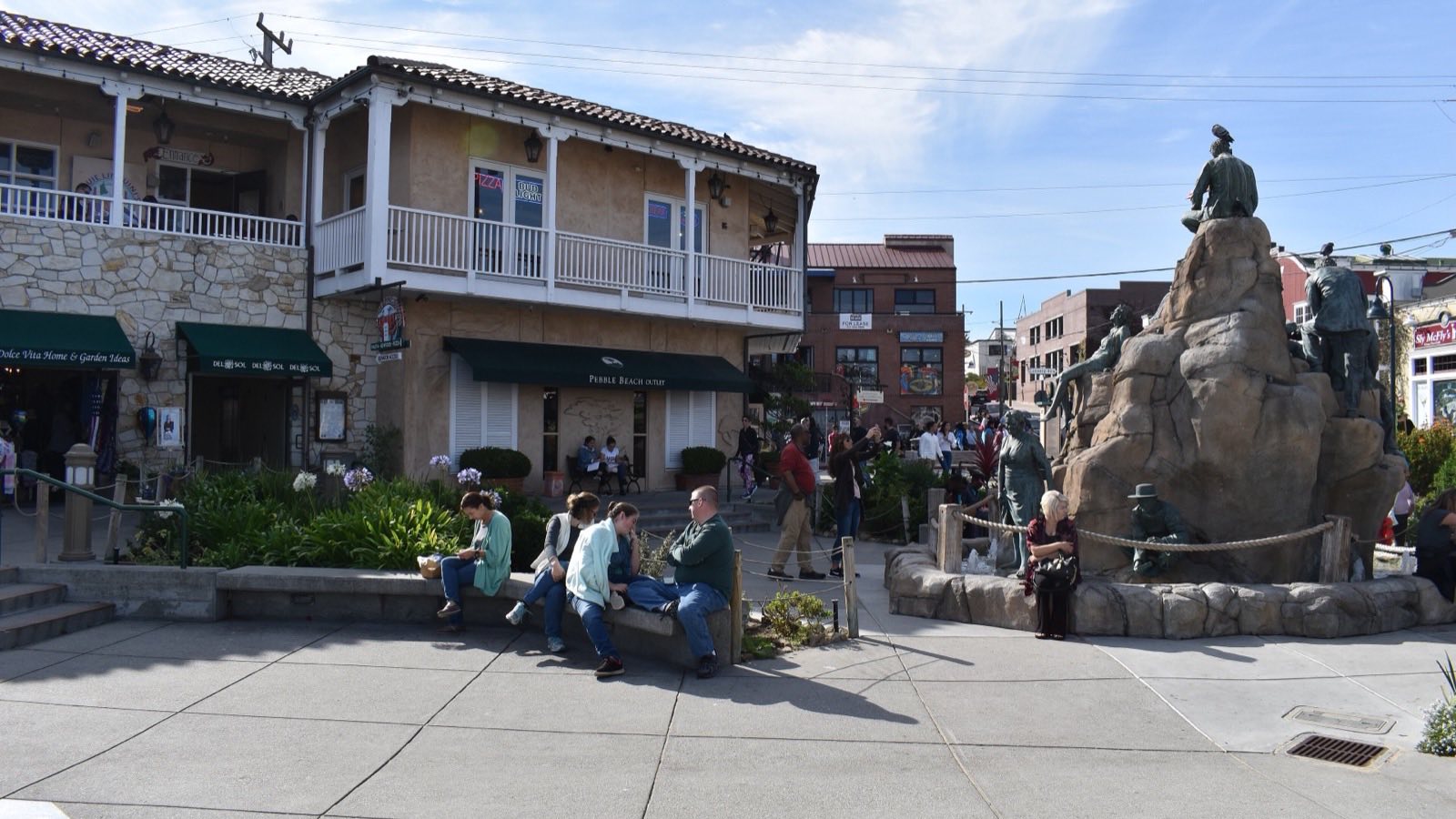 Cannery Row in Monterey with visitors outside shops and restaurants near the Steinbeck monument
